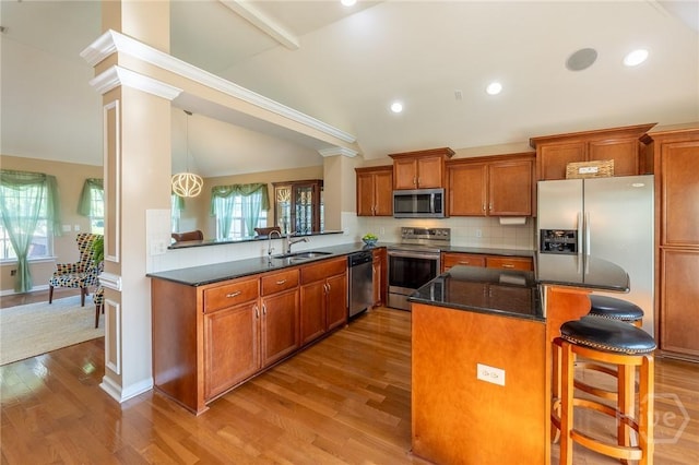 9 Sweetwater Ct, Savannah, GA 31419 - kitchen with stainless steel appliances, lofted ceiling, wood finished floors, brown cabinets, and a breakfast bar area