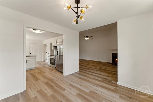 413 Roberts Way, Rincon, GA 31326 - kitchen with appliances with stainless steel finishes, white cabinetry, light wood-type flooring, a lit fireplace, and open floor plan