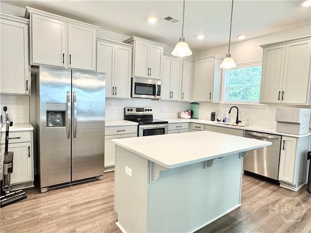134 Melody Dr, Pooler, GA 31322 - kitchen with stainless steel appliances, backsplash, light wood finished floors, a center island, and light countertops