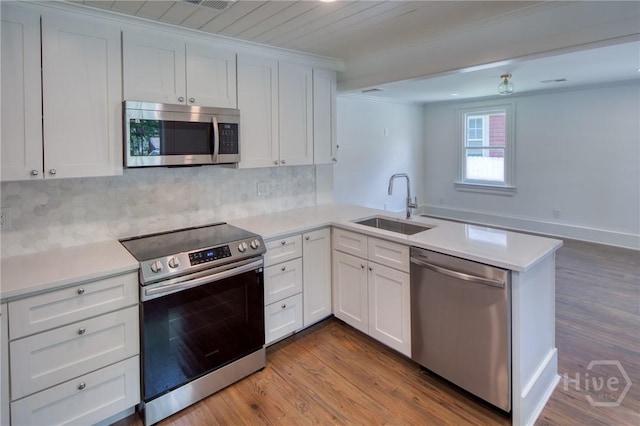 2125 Atlantic Ave, Savannah, GA 31401 - kitchen featuring stainless steel appliances, a peninsula, wood finished floors, light countertops, and crown molding