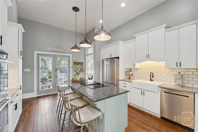 2309 Whitaker St, Savannah, GA 31401 - kitchen with appliances with stainless steel finishes, a kitchen island, white cabinetry, backsplash, and dark wood-type flooring