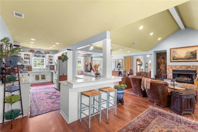 2441 Bovine Rd, Sylvania, GA 30467 - kitchen with freestanding refrigerator, wood finished floors, a fireplace, a breakfast bar, and recessed lighting