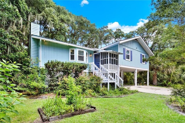 119 Catalina Dr, Tybee Island, GA 31328 - rear view of house with a carport, a chimney, a sunroom, driveway, and a lawn