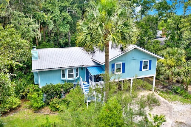 119 Catalina Dr, Tybee Island, GA 31328 - view of front of property featuring a carport, dirt driveway, a metal roof, stairway, and a chimney