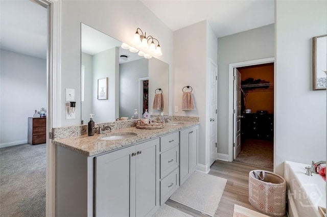 106 Cobbleton Dr, Rincon, GA 31326 - bathroom with double vanity, a walk in closet, a bath, and wood finished floors