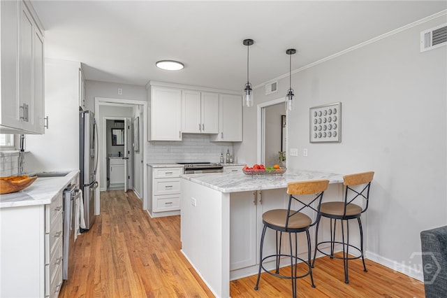 397 Hunt Dr, Savannah, GA 31406 - kitchen featuring a peninsula, stainless steel appliances, a breakfast bar area, decorative backsplash, and white cabinetry