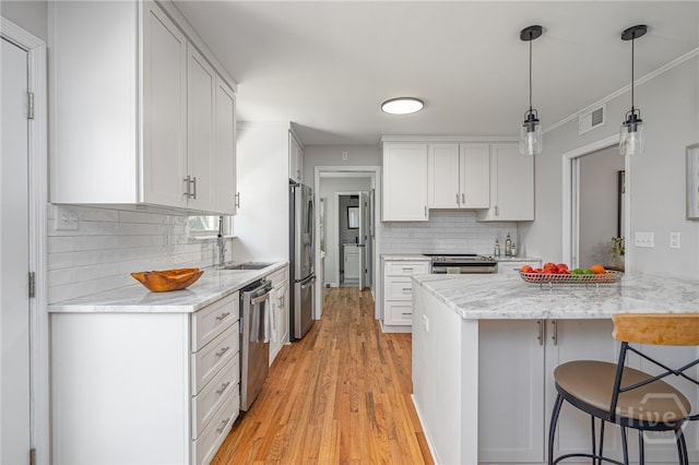 397 Hunt Dr, Savannah, GA 31406 - kitchen featuring stainless steel appliances, a kitchen breakfast bar, white cabinetry, backsplash, and light wood-type flooring