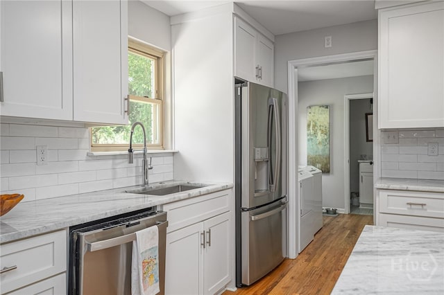 397 Hunt Dr, Savannah, GA 31406 - kitchen featuring stainless steel appliances, washer and dryer, white cabinets, light wood-type flooring, and light stone countertops