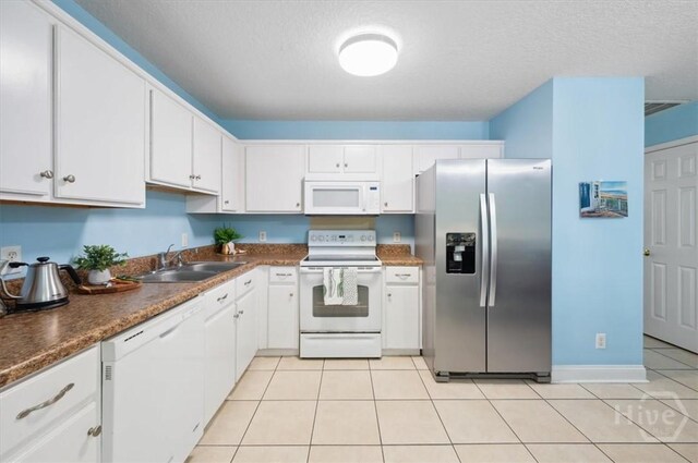 275 Carter St, Richmond Hill, GA 31324 - kitchen with white appliances, white cabinets, dark countertops, light tile patterned flooring, and a textured ceiling