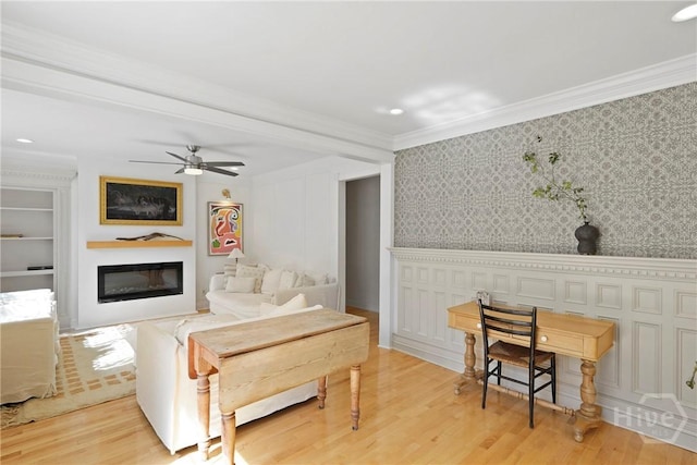 209 E 66th St, Savannah, GA 31405 - living room featuring a glass covered fireplace, crown molding, light wood finished floors, wallpapered walls, and ceiling fan