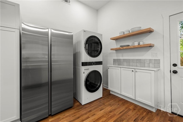 731 E 34th St, Savannah, GA 31401 - washroom featuring stacked washing machine and dryer, cabinet space, and wood finished floors