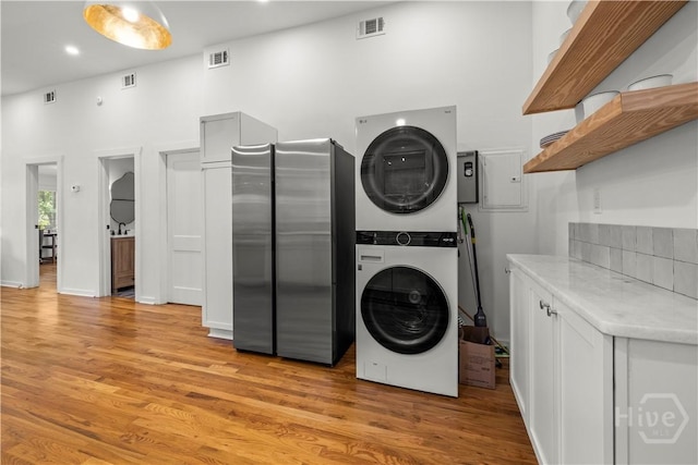 731 E 34th St, Savannah, GA 31401 - laundry room with stacked washing machine and dryer, a towering ceiling, and light wood-type flooring