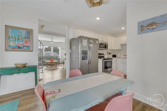 13 Izlar Ave, Tybee Island, GA 31328 - kitchen with stainless steel appliances, white cabinetry, wood finished floors, light countertops, and recessed lighting