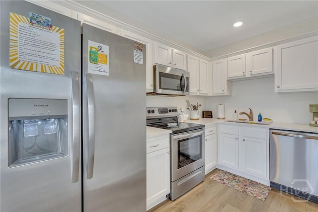 13 Izlar Ave, Tybee Island, GA 31328 - kitchen featuring appliances with stainless steel finishes, light countertops, white cabinets, light wood-style floors, and recessed lighting