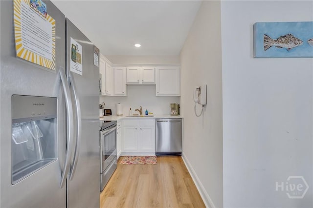13 Izlar Ave, Tybee Island, GA 31328 - kitchen featuring appliances with stainless steel finishes, light wood finished floors, white cabinetry, light countertops, and recessed lighting