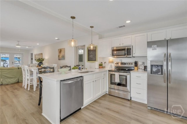 13 Izlar Ave, Tybee Island, GA 31328 - kitchen with appliances with stainless steel finishes, open floor plan, white cabinets, a peninsula, and recessed lighting