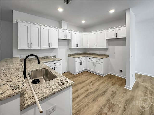 1031 Milton St, Savannah, GA 31405 - kitchen with light stone countertops, white cabinets, light wood-style flooring, and recessed lighting