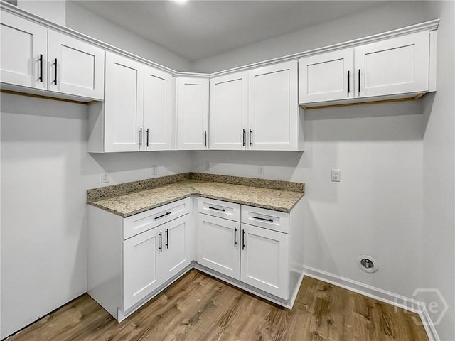 1031 Milton St, Savannah, GA 31405 - kitchen featuring wood finished floors, light stone countertops, and white cabinetry