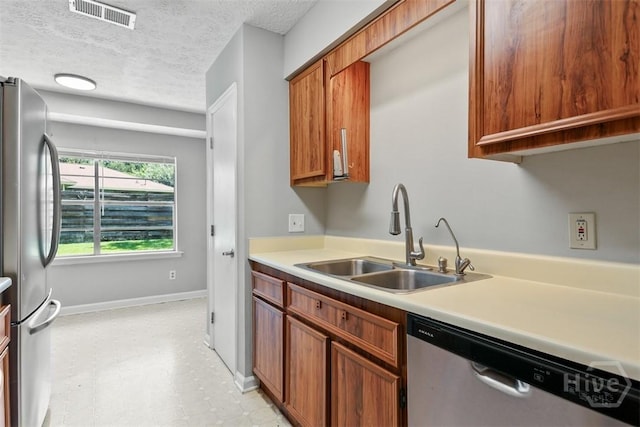 904 Mill Dr, Savannah, GA 31419 - kitchen featuring stainless steel appliances, light countertops, brown cabinetry, light floors, and a textured ceiling