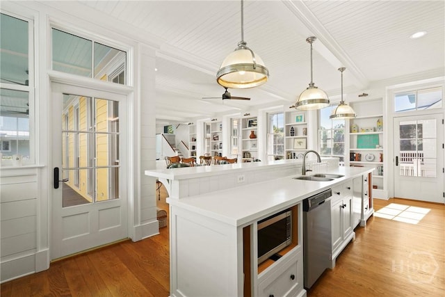 3 Palmwood Ct, Tybee Island, GA 31328 - kitchen featuring appliances with stainless steel finishes, light wood finished floors, light countertops, decorative light fixtures, and a center island with sink