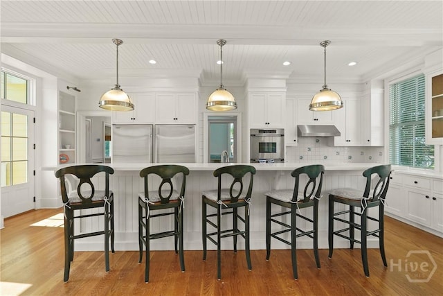 3 Palmwood Ct, Tybee Island, GA 31328 - kitchen featuring under cabinet range hood, appliances with stainless steel finishes, white cabinetry, light countertops, and light wood finished floors