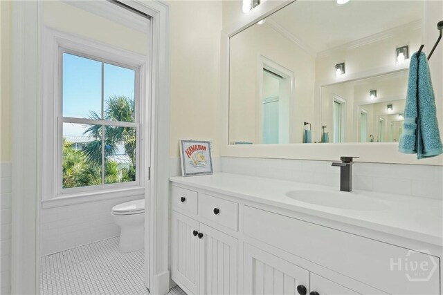 3 Palmwood Ct, Tybee Island, GA 31328 - bathroom with plenty of natural light, vanity, ornamental molding, a wainscoted wall, and tile patterned flooring