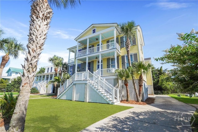 3 Palmwood Ct, Tybee Island, GA 31328 - coastal home with covered porch, a balcony, stairway, and a front yard
