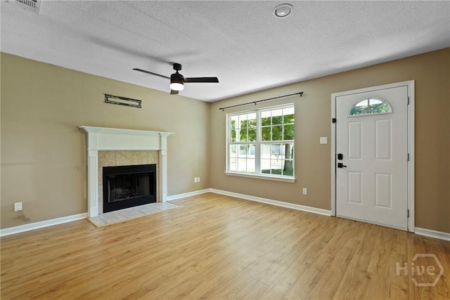 7305 Leghorn St, Savannah, GA 31406 - unfurnished living room featuring wood finished floors, a ceiling fan, a tiled fireplace, and a textured ceiling