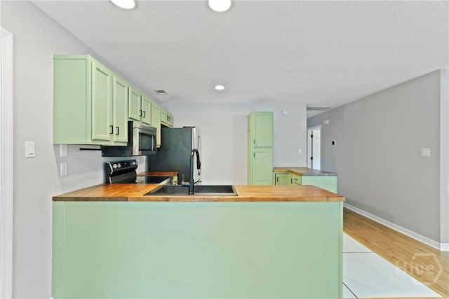 7305 Leghorn St, Savannah, GA 31406 - kitchen featuring butcher block counters, green cabinets, a peninsula, stainless steel appliances, and recessed lighting