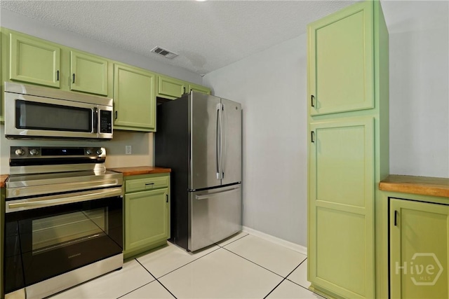 7305 Leghorn St, Savannah, GA 31406 - kitchen featuring appliances with stainless steel finishes, green cabinetry, light tile patterned floors, a textured ceiling, and butcher block counters