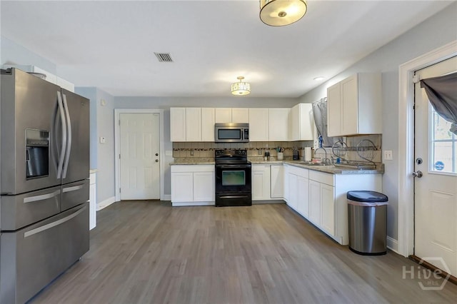 243 Forest St NE, Ludowici, GA 31316 - kitchen with stainless steel appliances, white cabinetry, and wood finished floors