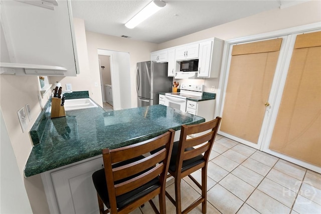 178 Junco Way, Savannah, GA 31419 - kitchen featuring black microwave, white electric range, freestanding refrigerator, dark countertops, and a peninsula