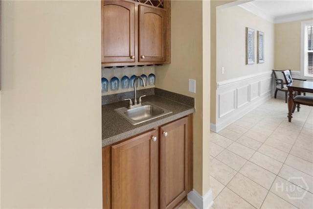 903 River Oaks Dr Unit 903, Richmond Hill, GA 31324 - kitchen with dark countertops, light tile patterned floors, crown molding, brown cabinetry, and wainscoting