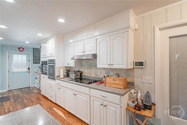 124 Drennon Dr, Jesup, GA 31545 - kitchen featuring black electric stovetop, backsplash, white cabinetry, oven, and crown molding