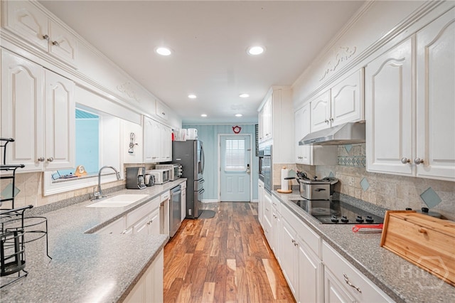 124 Drennon Dr, Jesup, GA 31545 - kitchen featuring under cabinet range hood, stainless steel appliances, white cabinetry, light wood-style flooring, and decorative backsplash