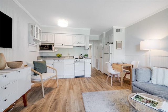 1217 Bay St Unit 109B, Tybee Island, GA 31328 - kitchen featuring white appliances, light wood-style floors, white cabinetry, ornamental molding, and open floor plan