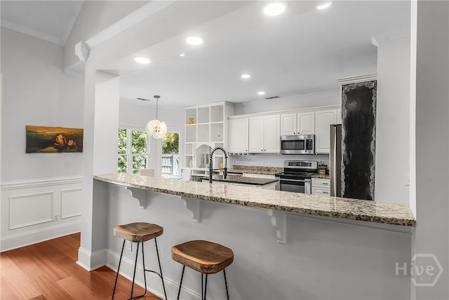 17 Hickory Grove Pt, Savannah, GA 31405 - kitchen featuring stainless steel appliances, wood finished floors, light stone counters, white cabinets, and a breakfast bar area