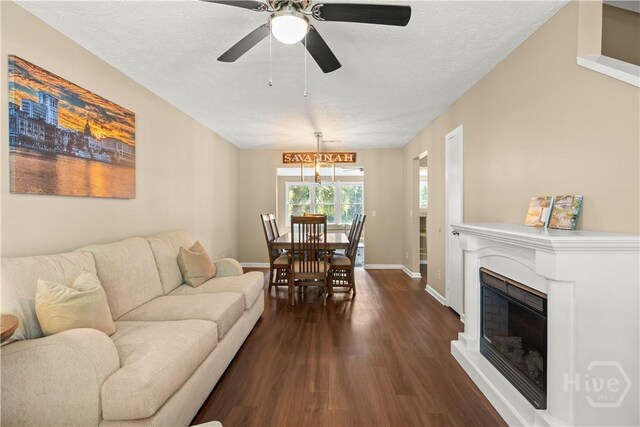310 Mapmaker Ln, Savannah, GA 31410 - living area with dark wood-style floors, a ceiling fan, a glass covered fireplace, and a textured ceiling