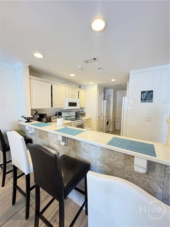 404 Butler Ave Unit 612, Tybee Island, GA 31328 - kitchen featuring white appliances, a kitchen bar, recessed lighting, ornamental molding, and light tile patterned flooring