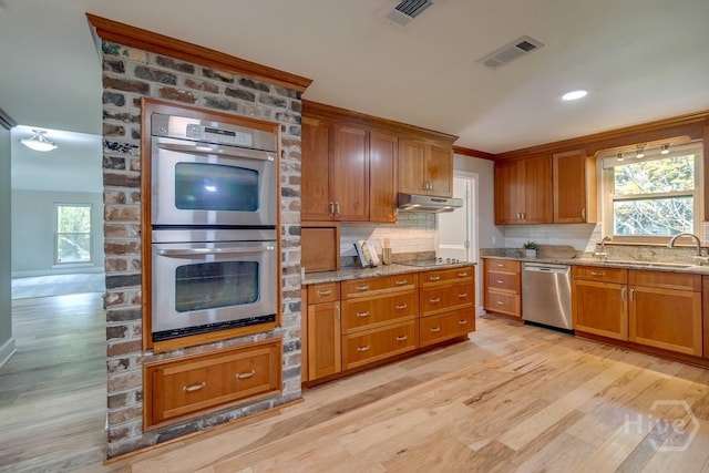 611 Benton Dr, Pooler, GA 31322 - kitchen featuring appliances with stainless steel finishes, light wood finished floors, brown cabinetry, tasteful backsplash, and ornamental molding