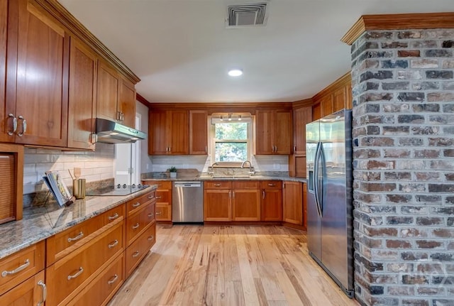 611 Benton Dr, Pooler, GA 31322 - kitchen with appliances with stainless steel finishes, brown cabinetry, light wood finished floors, under cabinet range hood, and light stone counters