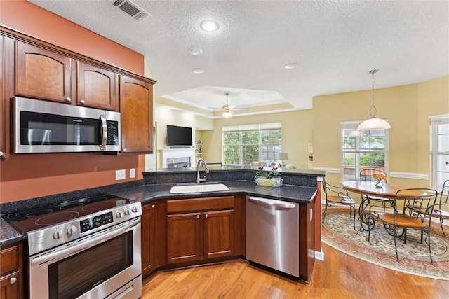 7 River Rock Rd, Savannah, GA 31419 - kitchen with appliances with stainless steel finishes, a raised ceiling, a peninsula, light wood-style flooring, and ceiling fan