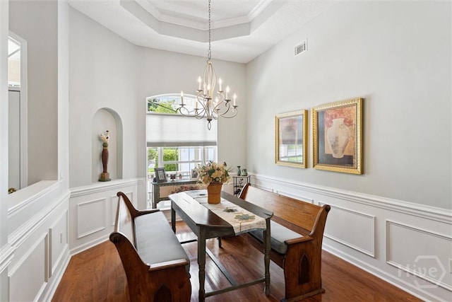 7 River Rock Rd, Savannah, GA 31419 - dining space featuring a chandelier, a raised ceiling, a decorative wall, wood finished floors, and wainscoting