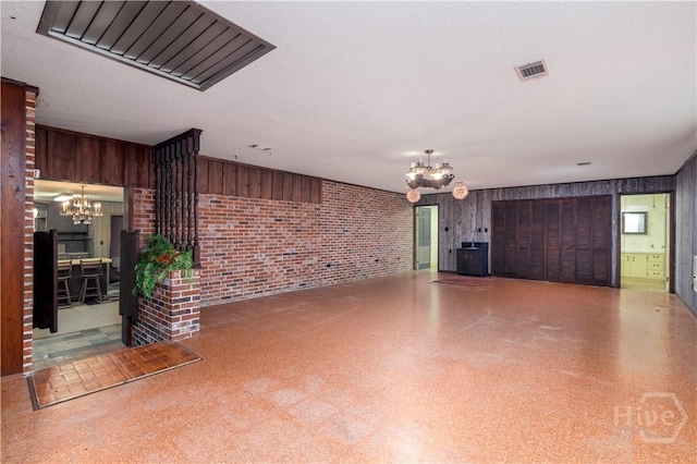 401 E Smith St, Claxton, GA 30417 - unfurnished living room with a chandelier, brick wall, and wooden walls