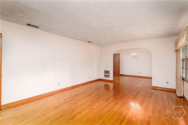 401 E Smith St, Claxton, GA 30417 - spare room with arched walkways, heating unit, light wood-type flooring, and a chandelier
