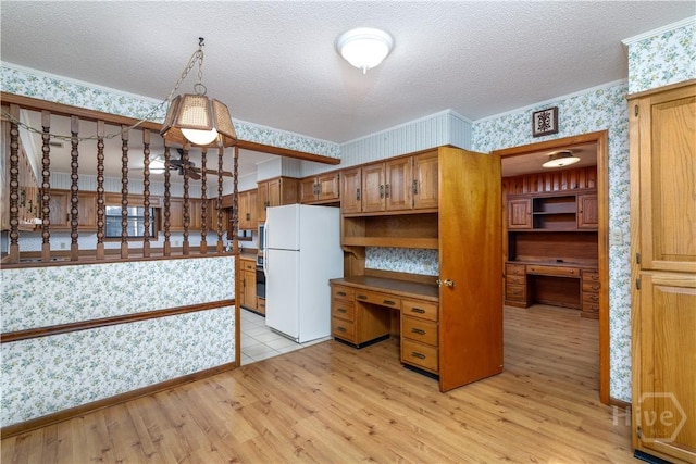 401 E Smith St, Claxton, GA 30417 - kitchen featuring freestanding refrigerator, wallpapered walls, light wood-type flooring, built in study area, and a textured ceiling