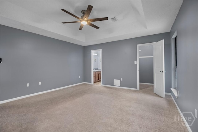 2 Brandle Cv, Savannah, GA 31405 - unfurnished bedroom featuring a tray ceiling, light carpet, ensuite bathroom, and a ceiling fan
