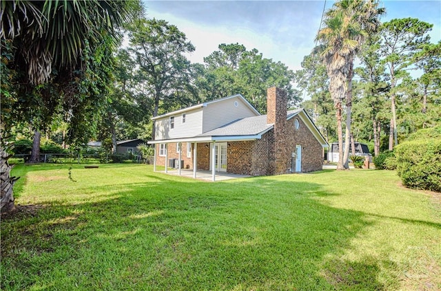 1003 Lora St, Savannah, GA 31410 - rear view of property with a chimney, brick siding, a yard, and a patio area