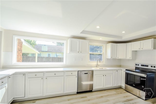 1003 Lora St, Savannah, GA 31410 - kitchen with stainless steel appliances, light wood-type flooring, white cabinets, recessed lighting, and a tray ceiling