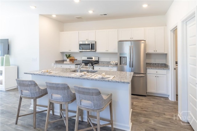 143 Crimson Ln, Savannah, GA 31302 - kitchen with stainless steel appliances, a kitchen island with sink, white cabinets, a breakfast bar area, and recessed lighting